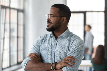 Successful African American startup leader looking out window with hands crossed. Millennial...