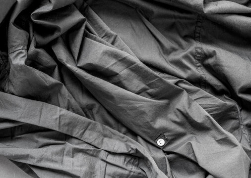 unpressed dark grey black casual dress shirt with seams - photographed from above with low or raking light - emphasis on texture and folds