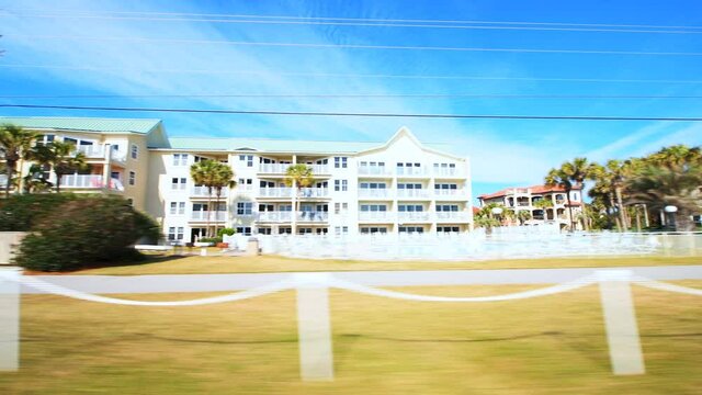 Point of view pov car driving shot on Destin by Miramar street road at Florida gulf of mexico coastal city with people walking by residential house condo apartment buildings
