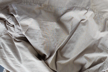 beige and white or light brown sand striped dress shirt with creases and folds - photographed from above with low or raking light - emphasis on texture and folds