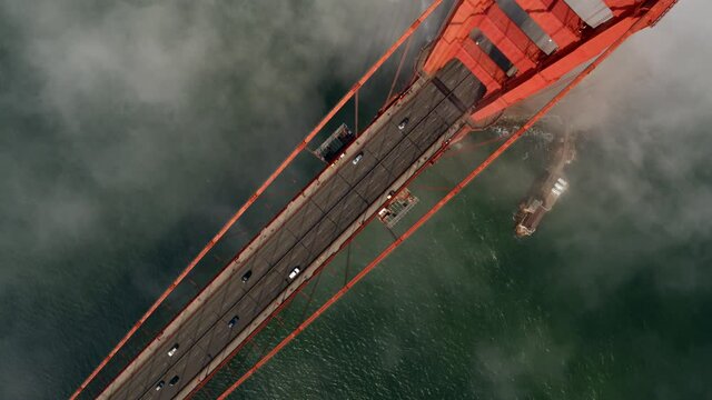 Cinematic aerial footage of fog engulfing the iconic and historic landmark the Golden Gate Bridge in San Francisco - California, USA