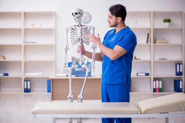 Young male doctor examining skeleton patient