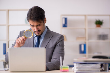 Young male employee auditor holding magnifying glass