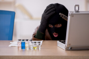 Young man in balaclava stealing vaccine from the lab