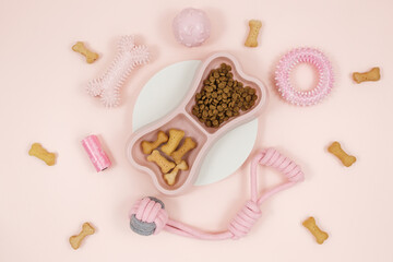 Set of pink accessories for your dog: bowl, toys, ball, bones, food on pink background. Pet care and training for pet owners.