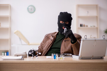 Young man in balaclava stealing vaccine from the lab