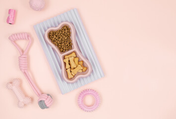 Set of pink accessories for your dog: bowl, toys, ball, bones, food on pink background. Pet care and training for pet owners.