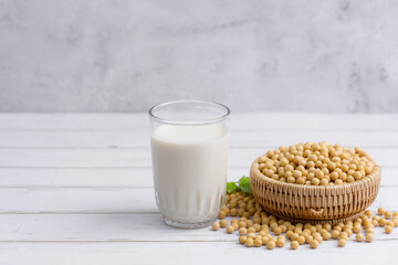 Soy and soy milk in a glass with soybeans in wooden bowl background