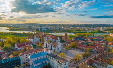 Deurstickers Aerial view of a sunny day in Kaunas city town hall square with towers of churches, castle, cathedral and Neris river around © Audrius