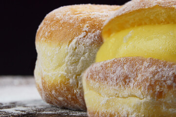 Berlin balls, known as Sonho in Brazil on wooden table with scattered icing sugar. It consists of a...