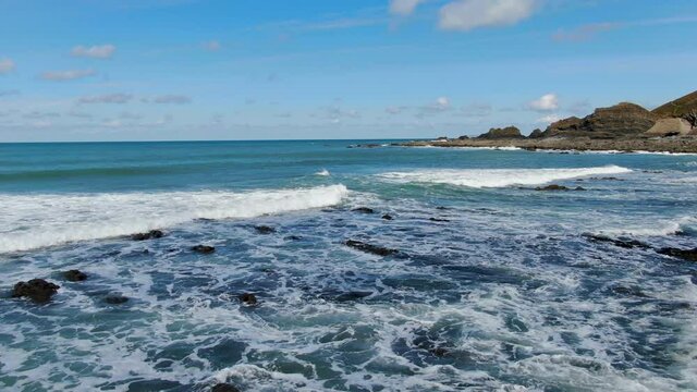 Aerial coastal shot of the waves crashing in the sea at Spekes Mill beach in Devon, UK