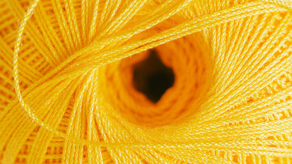 Close-up of a skein of thread. Textured illuminating yellow background.