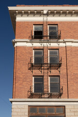 three windows with balconies on the facade of an abandoned brick hotel in a ghost town