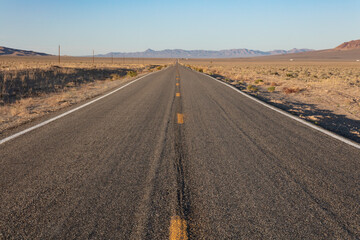 Deserted road under the Mojave Desert sun, heading straight towards the horizon