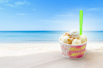 Coconut cream ice cream in paper cup with green plastic spoon over the beach, summer treat, happy summer