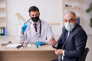 Obraz premium Old businessman visiting young male doctor in vaccination concep