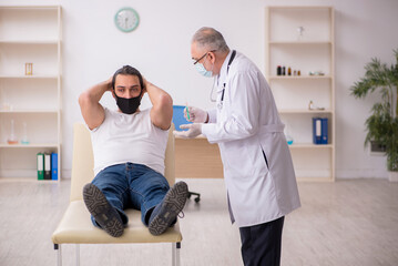 Fototapeta premium Young male patient visiting old doctor in vaccination concept