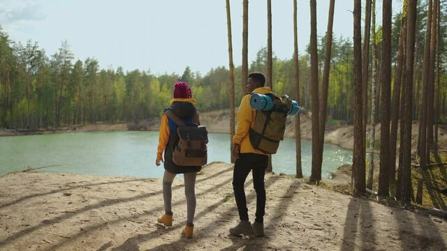 Hiking people. Hiker two african couple man and woman in the mountain. Two black woman and man trekkers walking through forest path with backpack. Slow motion