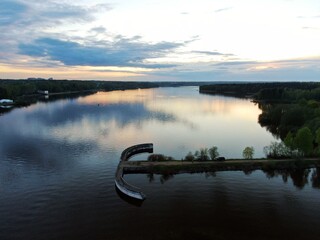 Aerial view sunset on the river. Colorful clouds are reflected in the water. Beautiful panorama of nature at sunset.