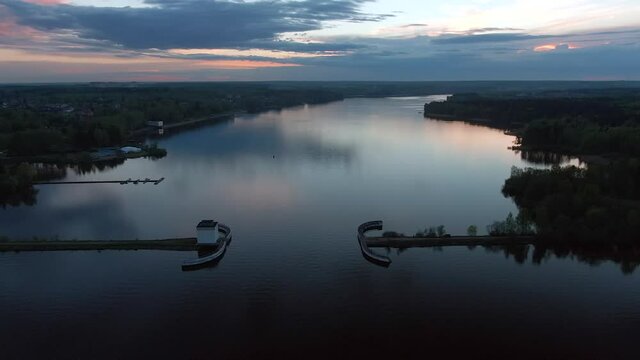 Aerial view flight at sunset above the river. Colorful clouds are reflected in the water. Beautiful panorama of nature at sunset.
