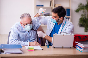 Young male doctor visiting old businessman at workplace