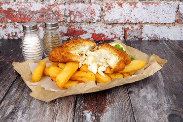 Battered cod fish and chips meal wrapped in brown paper - obrazy, fototapety, plakaty