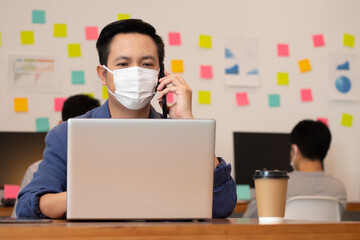 Business man working job on labtop and wering mask in office.