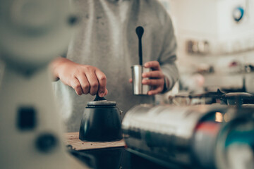 Barista measure coffee powder and brewing black moka coffee using moka coffee maker.