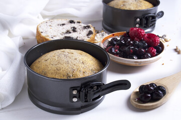  fresh baked banana cake in metal spring form with fruits and berries on plate. White background, healthy food concept