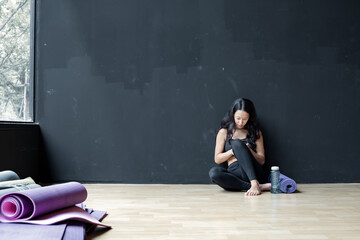 Woman playing smartphone after exercise in gym.