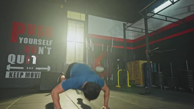 Caucasian male athlete doing exercise by jump burpee position in gym.