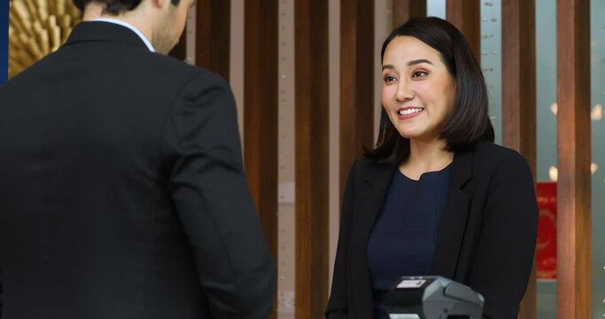 Friendly receptionist woman working at desk in hotel lobby