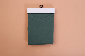 Folded green tshirts with packaging on wooden background