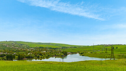 Fototapeta na wymiar Lake by a village with green hills