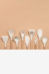 Cooking utensil set. Silicone kitchen tools with wooden handle on beige background with copy space. Top view Flat lay