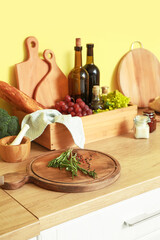Cutting board with rosemary, peppercorns and different products on kitchen table