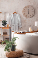 Stylish interior of modern bathroom with burning candles and houseplants