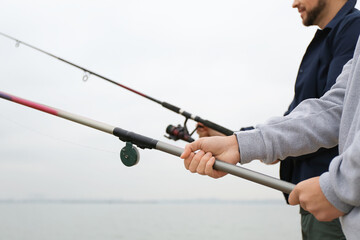 Father and son fishing together on river