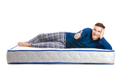 Young man lying on soft mattress and showing thumb-up against white background