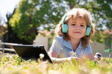 Cute american toddler school boy online learning, writing book in the park. Study outdoor.