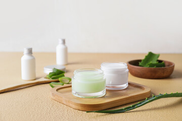 Jar with natural cream and aloe leaves on color background