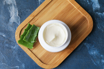 Jar with natural cream and aloe leaves on color background