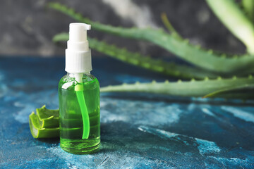 Bottle with natural cosmetic product and aloe leaves on color background