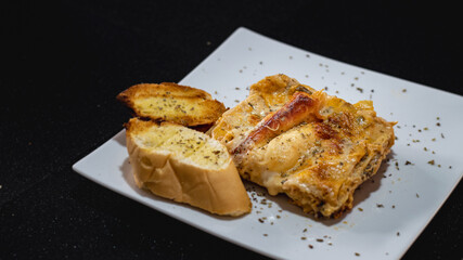 Lasaña de pollo acompañada de pan