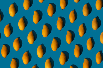 Trendy sunlight summer pattern made with yellow mango on bright light blue background. Minimal summer concept.