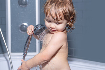 Little baby taking bath, closeup face portrait of smiling boy, health care and kids hygiene. Child bathing under a shower.