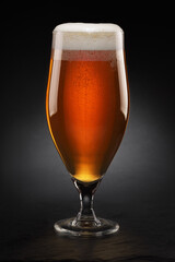 Cup with fresh beer with cap of foam on a black.