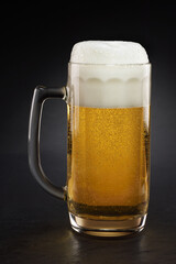 Stein with fresh beer with cap of foam on a black.