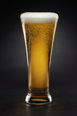 Mug with fresh beer with cap of foam on a black.