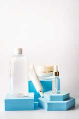 Glass cosmetic bottle with oil or serum and cream for skin care on special podium of blue color. Natural skin care concept.